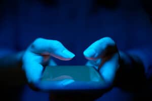Person hält Smartphone in blauem Licht